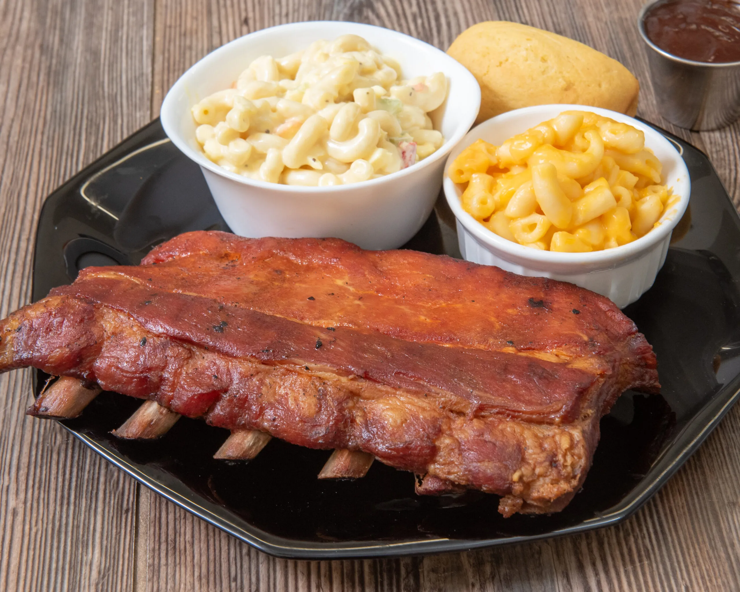 Smoked BBQ ribs served with macaroni salad, mac and cheese and cornbread